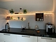 Witte wandplanken van Strackk met LED verlichting aan met houten kastje en wijnglazenrek boven keuken